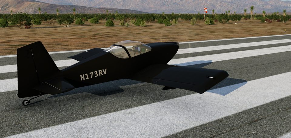 A black RV-7 on a runway, seen from the side, with desert and mountains behind it.